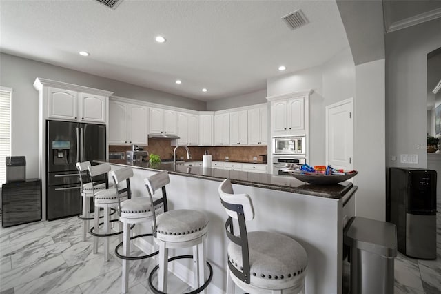 kitchen featuring visible vents, white cabinets, appliances with stainless steel finishes, marble finish floor, and backsplash