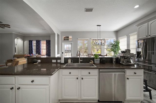 kitchen featuring visible vents, arched walkways, a sink, stainless steel appliances, and open floor plan