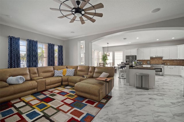 living area with recessed lighting, arched walkways, ceiling fan, crown molding, and marble finish floor