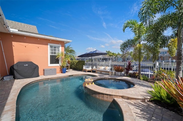 view of pool with grilling area, an in ground hot tub, and fence