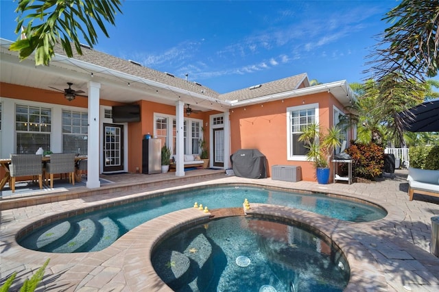 rear view of property featuring stucco siding, a patio, an in ground hot tub, and a ceiling fan