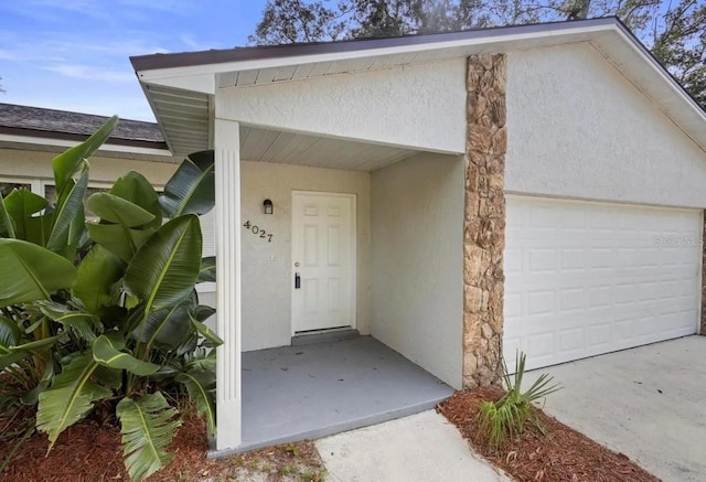 view of exterior entry featuring a garage and stucco siding