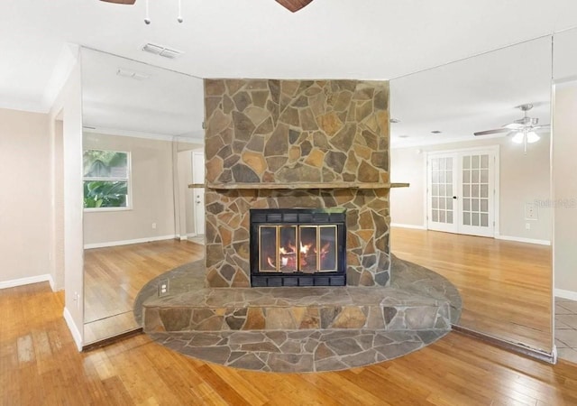 living room featuring ceiling fan, a fireplace, visible vents, ornamental molding, and wood-type flooring