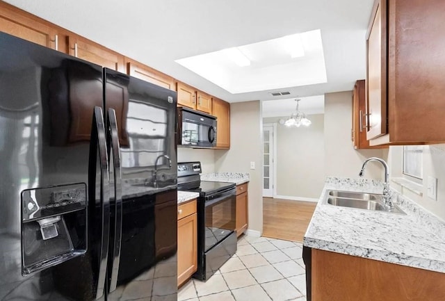 kitchen featuring light tile patterned flooring, a sink, light countertops, brown cabinets, and black appliances