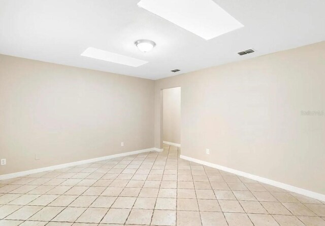 empty room with a skylight, visible vents, and baseboards