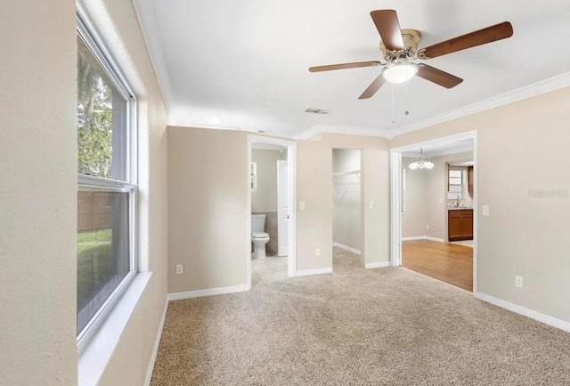 empty room featuring carpet, visible vents, ornamental molding, baseboards, and ceiling fan with notable chandelier