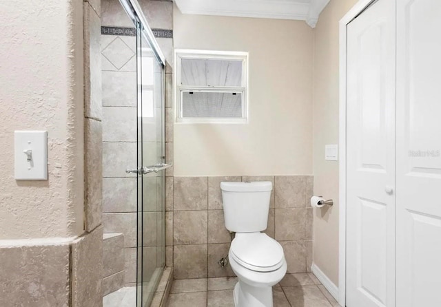 full bathroom featuring toilet, tile walls, a shower stall, tile patterned floors, and crown molding