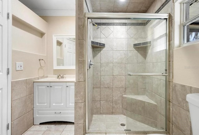 bathroom with a stall shower, tile walls, vanity, and tile patterned floors