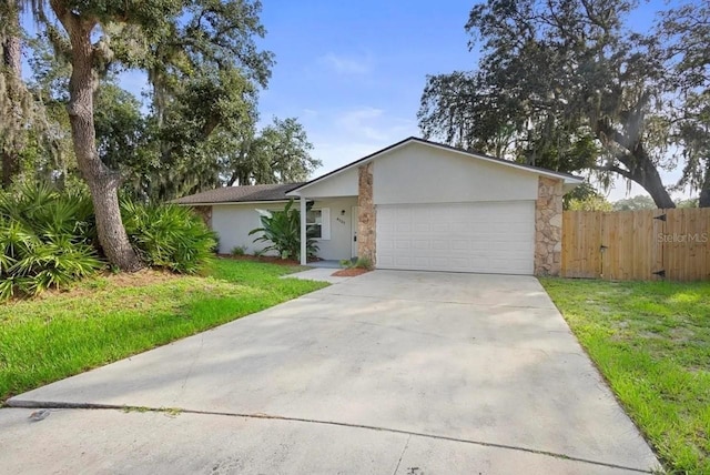 view of front of house with driveway, stucco siding, an attached garage, fence, and a front yard