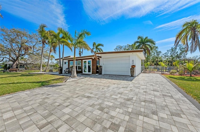 view of front of home featuring an attached garage, fence, decorative driveway, a front lawn, and stucco siding