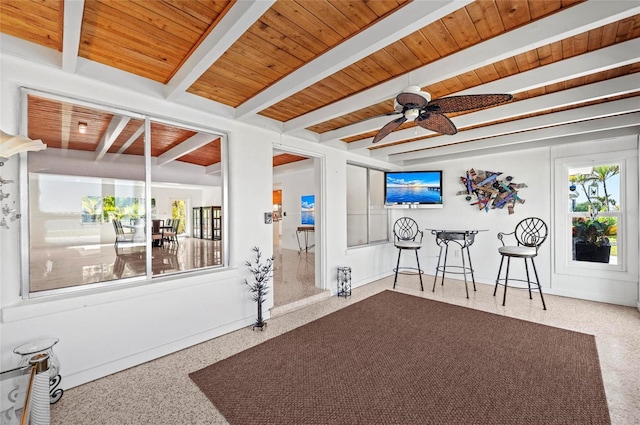 sitting room with wood ceiling, a ceiling fan, beamed ceiling, and speckled floor