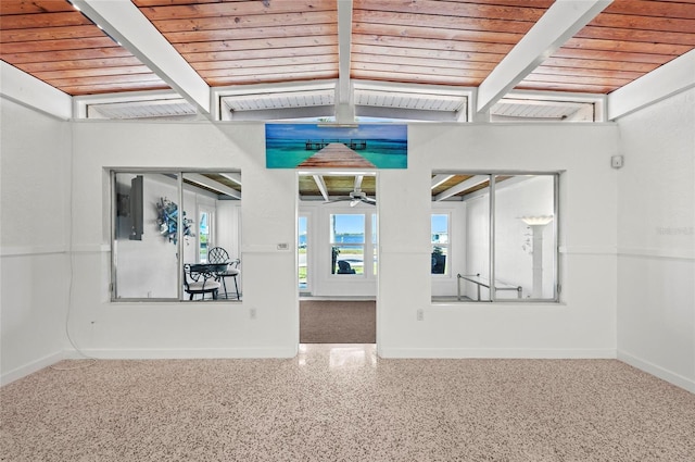 spare room with ceiling fan, wooden ceiling, speckled floor, baseboards, and beamed ceiling