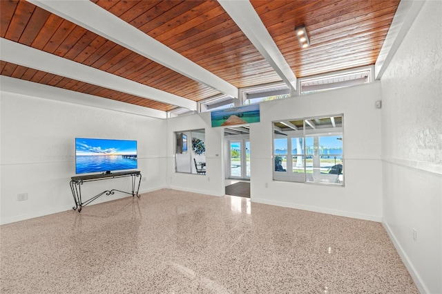 unfurnished living room featuring baseboards, beamed ceiling, and speckled floor