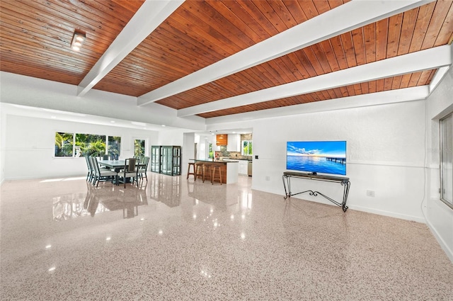 unfurnished living room with wood ceiling, baseboards, beamed ceiling, and speckled floor