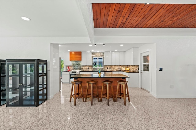 dining area featuring wooden ceiling, baseboards, light speckled floor, and beam ceiling