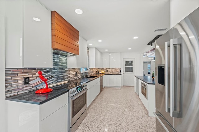 kitchen with stainless steel appliances, dark countertops, white cabinetry, a sink, and modern cabinets