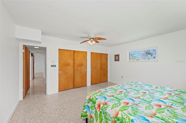 bedroom featuring ceiling fan, baseboards, light speckled floor, and two closets