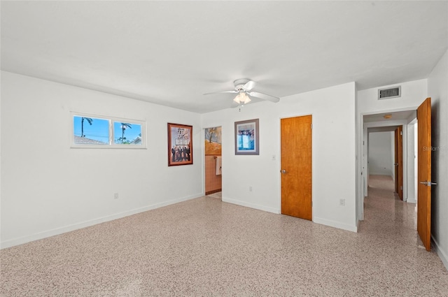 unfurnished bedroom with light speckled floor, visible vents, baseboards, and a ceiling fan