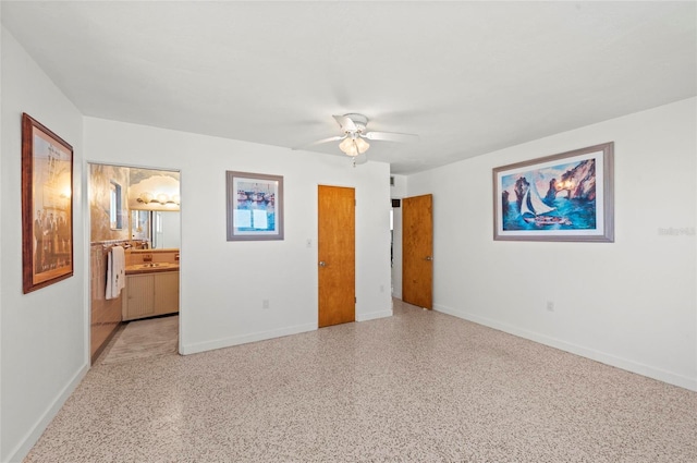 unfurnished bedroom with speckled floor, ensuite bath, a ceiling fan, and baseboards