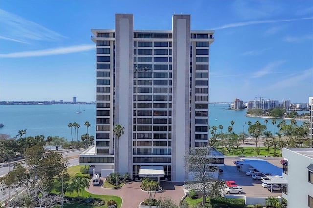 view of building exterior with uncovered parking, a water view, and a city view