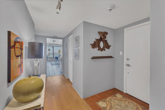 hallway with a textured ceiling and wood finished floors