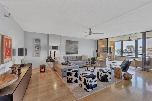 living area featuring light wood-style flooring, ceiling fan, and a textured ceiling