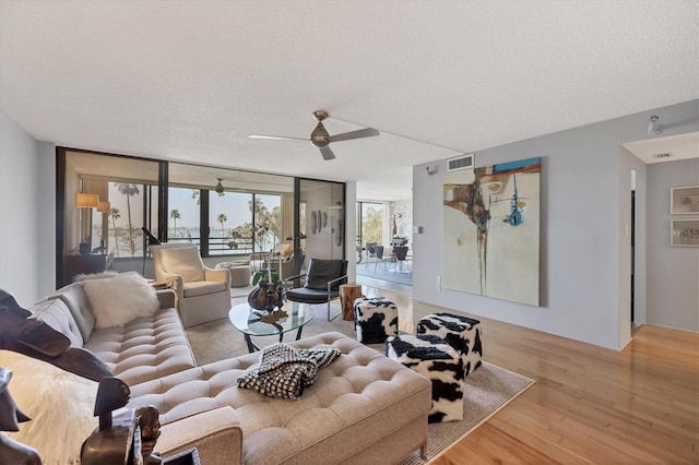 living room with visible vents, a ceiling fan, wood finished floors, expansive windows, and a textured ceiling