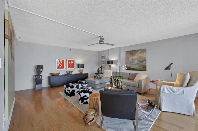 living area with a textured ceiling, a ceiling fan, and wood finished floors