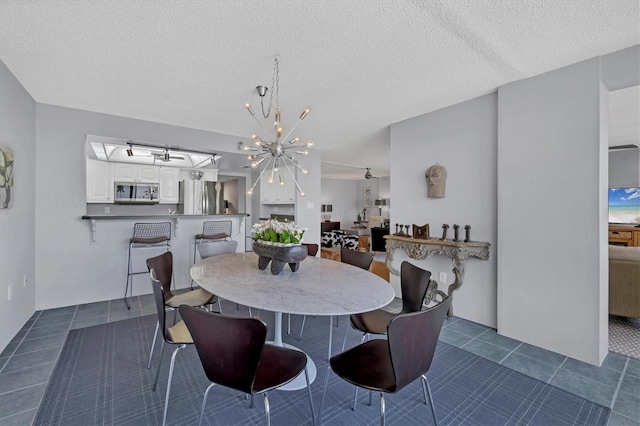 dining room with a notable chandelier, a textured ceiling, and dark tile patterned flooring