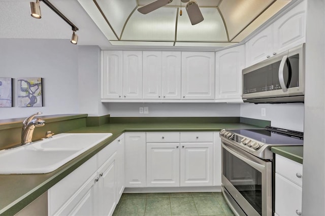 kitchen with white cabinets, dark countertops, appliances with stainless steel finishes, a sink, and light tile patterned flooring