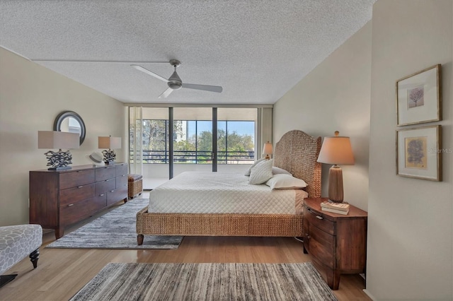 bedroom featuring expansive windows, access to outside, a textured ceiling, and wood finished floors