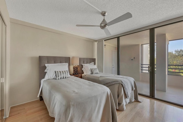 bedroom featuring light wood-style floors, a textured ceiling, a ceiling fan, and a closet