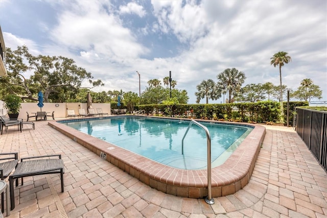 community pool with a patio and fence