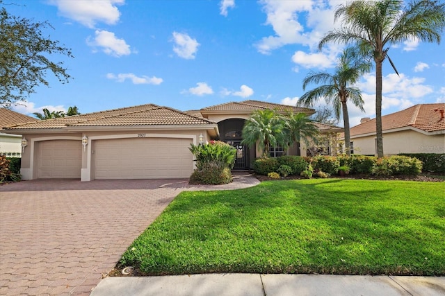 mediterranean / spanish home with a garage, a front lawn, decorative driveway, and stucco siding