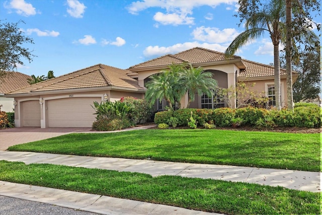 mediterranean / spanish-style house featuring driveway, a tile roof, an attached garage, a front lawn, and stucco siding