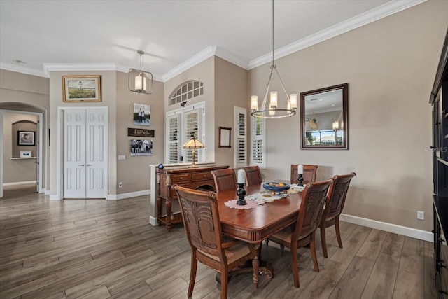 dining room with arched walkways, baseboards, wood finished floors, and crown molding