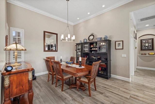 dining room with visible vents, baseboards, light wood finished floors, an inviting chandelier, and crown molding