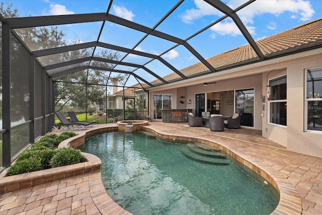 view of swimming pool with a ceiling fan, glass enclosure, a pool with connected hot tub, and a patio area