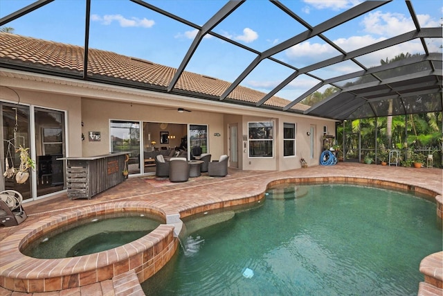 view of pool featuring a lanai, a pool with connected hot tub, outdoor lounge area, and a patio