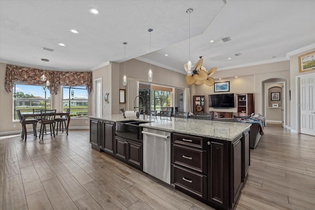 kitchen with arched walkways, a sink, light wood-style floors, open floor plan, and stainless steel dishwasher