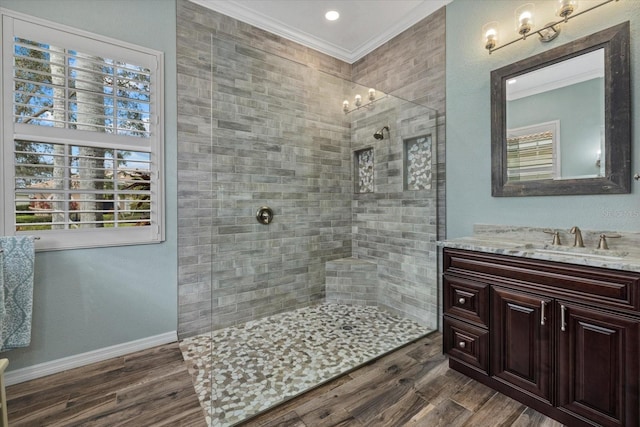 full bathroom featuring a walk in shower, wood finished floors, vanity, baseboards, and crown molding