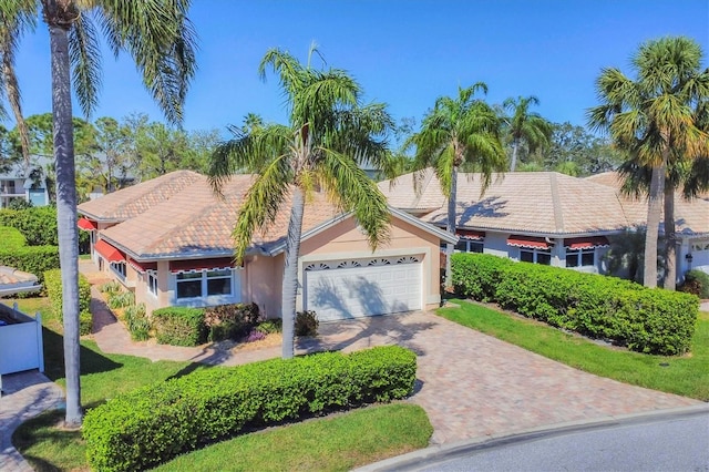 view of front of house featuring a garage, decorative driveway, a tile roof, and stucco siding