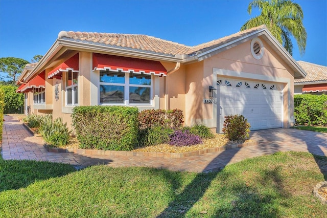 view of front of home with a tiled roof, a garage, driveway, and stucco siding