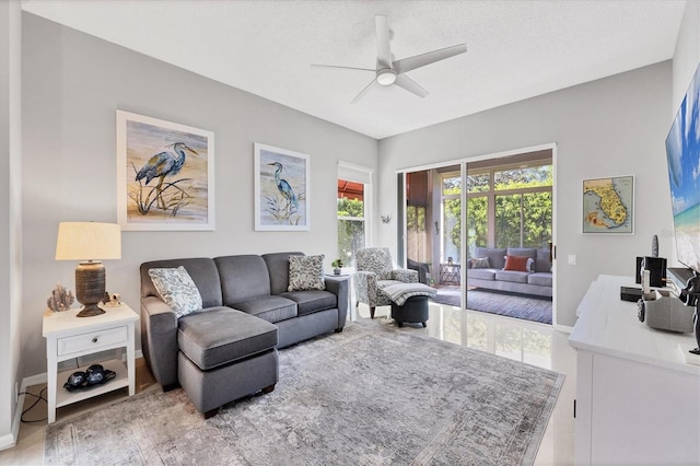 living area featuring a textured ceiling, baseboards, and ceiling fan