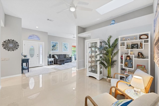 interior space with baseboards, visible vents, a skylight, and ceiling fan