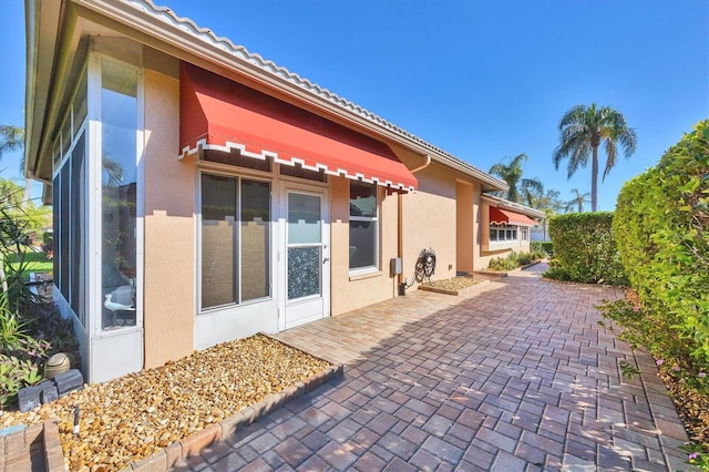 back of property featuring a patio, a tile roof, and stucco siding