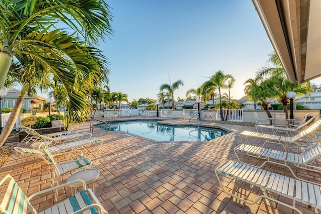 community pool with a patio area and fence