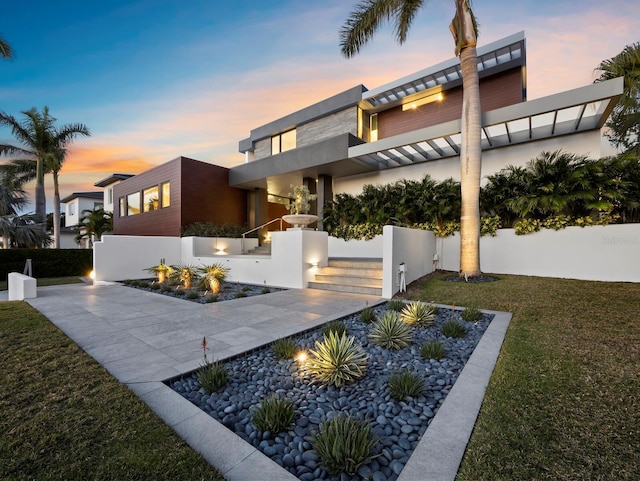 exterior space featuring driveway, stucco siding, fence, and a yard