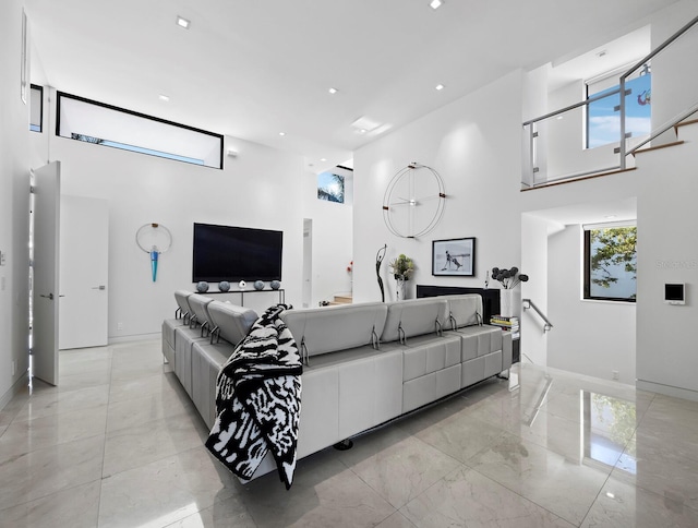 living room featuring marble finish floor, a high ceiling, baseboards, and recessed lighting