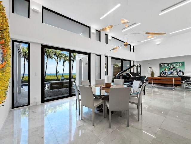 dining area featuring a towering ceiling and marble finish floor